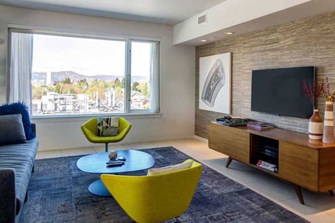 A living room with a blue sofa, yellow chair, and a television.
