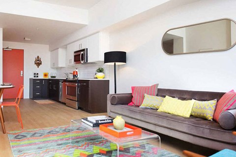 A living room with a grey couch and a rug on the floor.