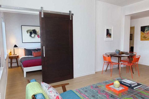 A room with a bed, a table and chairs, and a sliding door.