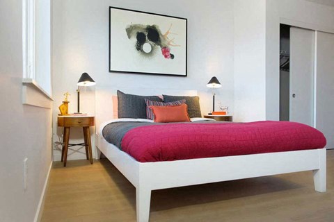 A bedroom with a white bed and a red blanket.