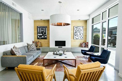 A modern living room with a grey couch, a coffee table, and a large window.