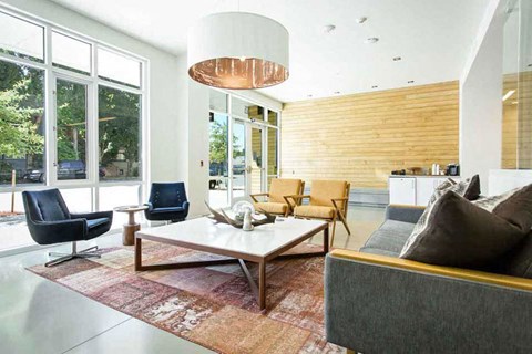 A modern living room with a grey couch, a wooden coffee table, and a large window.
