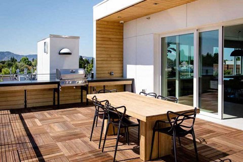 A wooden table with chairs is in front of a modern house.