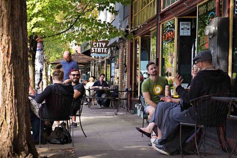 A group of people are sitting outside a bar called City State.
