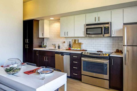 A modern kitchen with a white table and stainless steel appliances.