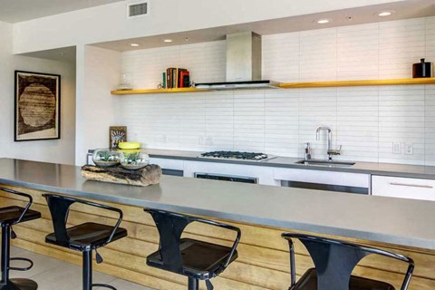 A modern kitchen with a long counter and bar stools.
