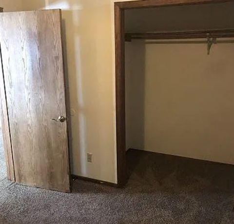 A room with a wooden door and a white wall.