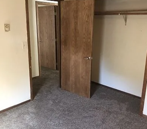 A room with a wooden door and carpeted floor.