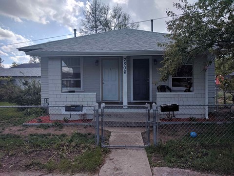 a small white house with a fence in front of it