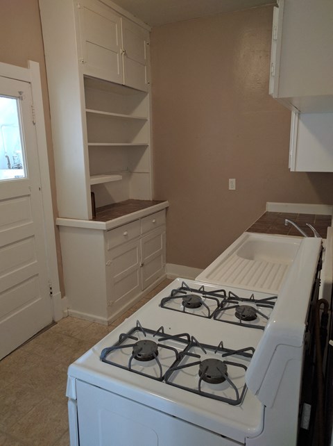 an empty kitchen with a stove and a cabinet