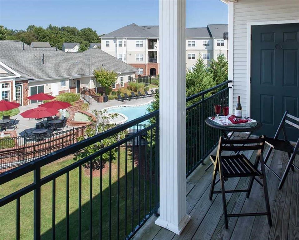 a balcony with a table and chairs overlooking a swimming pool