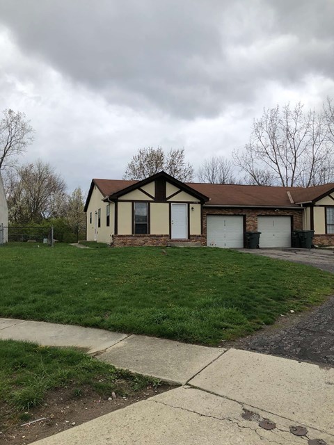 a house with white garage doors on a grass field