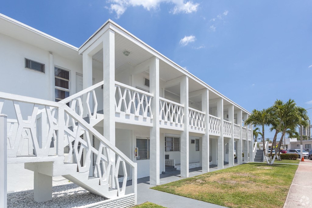 the outside of a white building with white stairs and a lawn