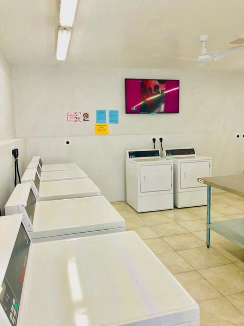 a laundry room with white appliances and a television on the wall