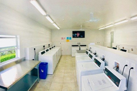 a laundry room filled with white washing machines and sinks