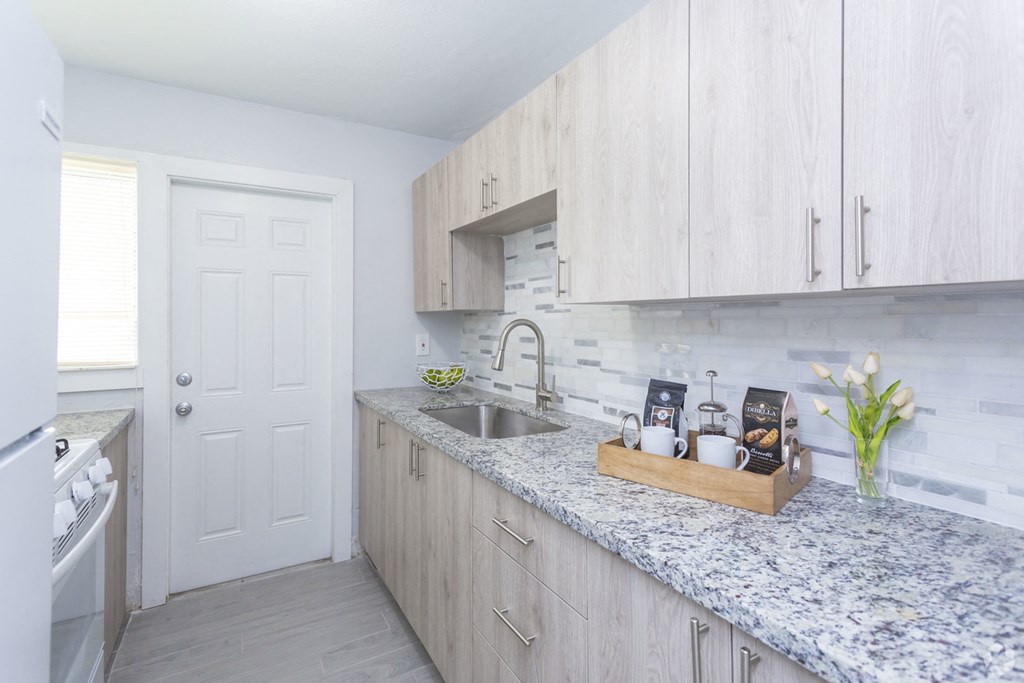 a kitchen with white cabinets and a marble counter top