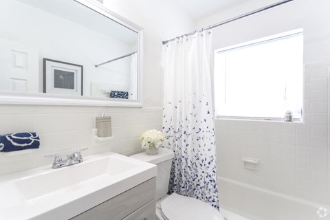 a white bathroom with a blue and white shower curtain