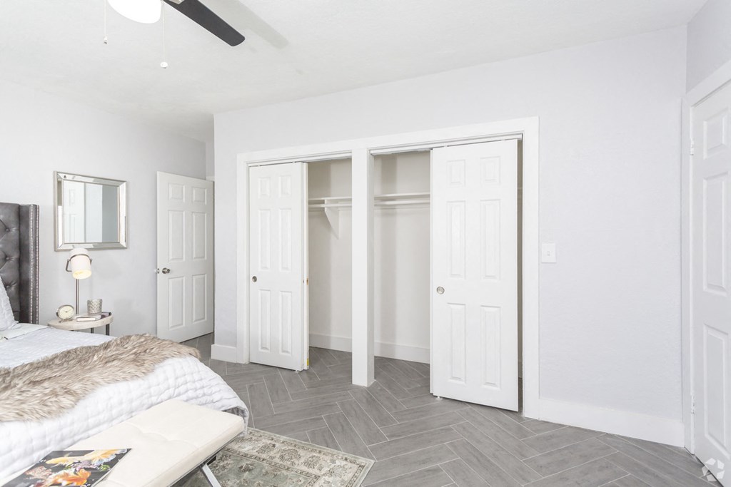 a bedroom with three closets and a bed and a grey tile floor