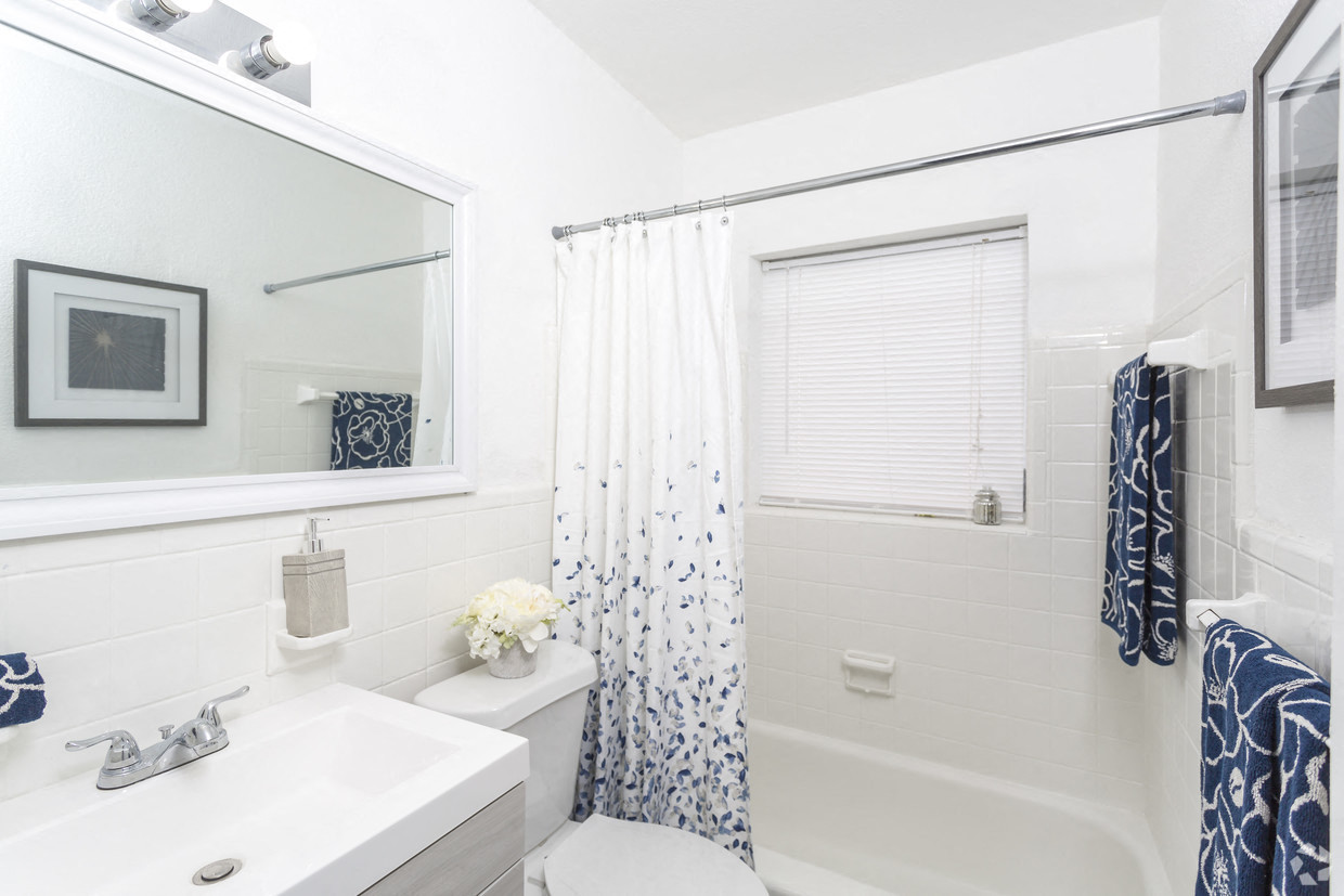 a white bathroom with a blue and white shower curtain