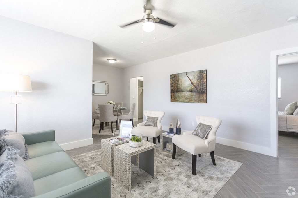 a living room with a couch and chairs and a ceiling fan