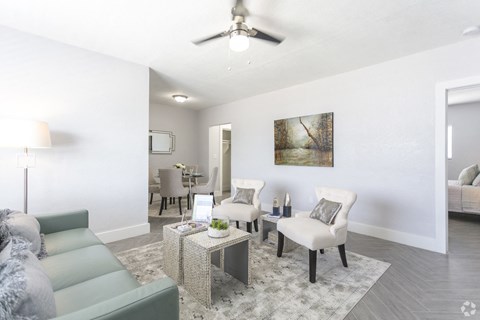 a living room with a couch and chairs and a ceiling fan