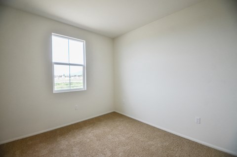 an empty room with a window and carpet