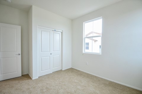 an empty bedroom with white walls and a window