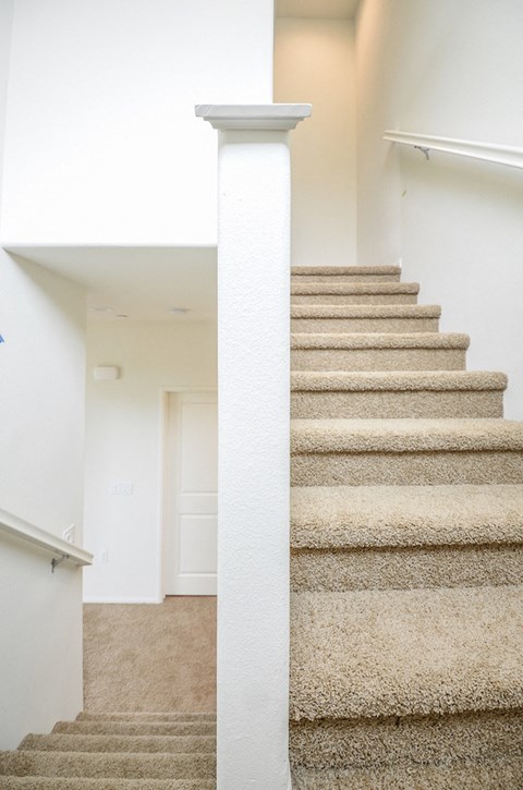 a staircase in a home with carpeted stairs and a white column