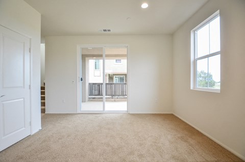 an empty living room with a door to a balcony