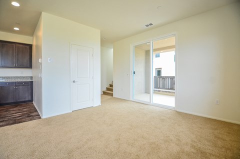 a living room and kitchen with a door to a balcony