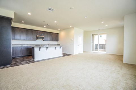 an empty living room and kitchen with a counter