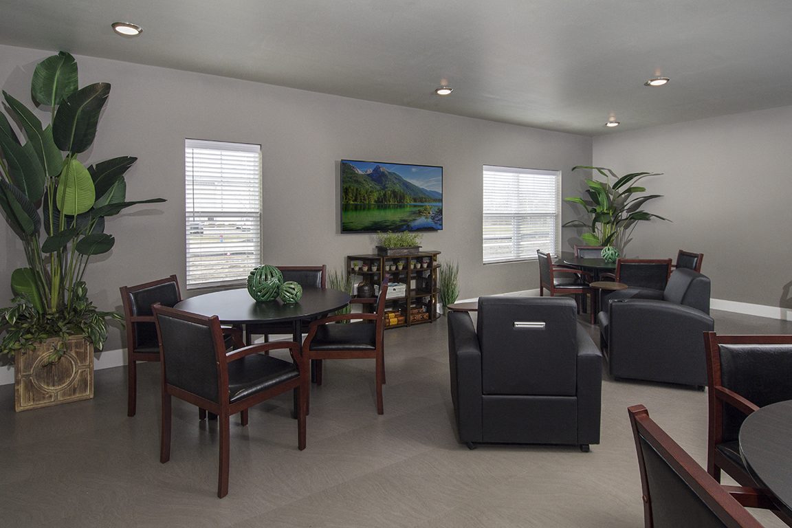 A living room with a painting of a landscape on the wall.