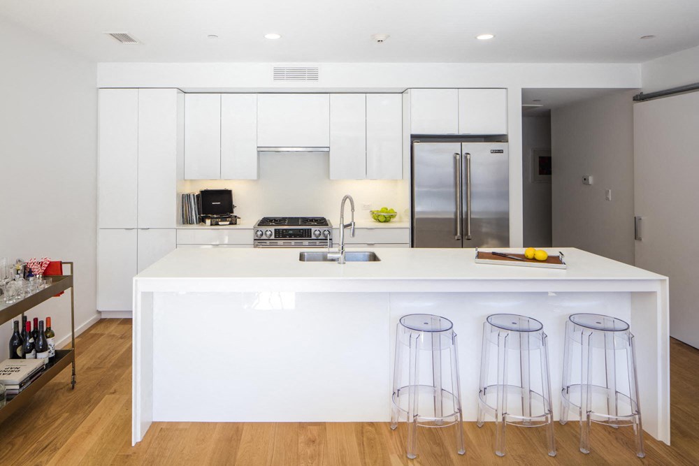 a white kitchen with three bar stools in front of a white counter top