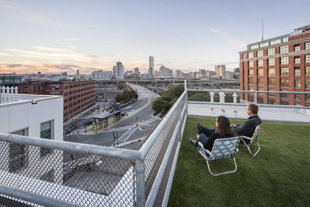 two people sitting on chairs on a rooftop overlooking the city