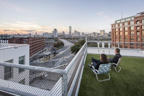 two people sitting on chairs on a rooftop overlooking the city
