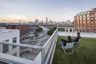 two people sitting on chairs on a rooftop overlooking the city