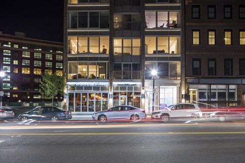 a city street at night with cars parked in front of a building