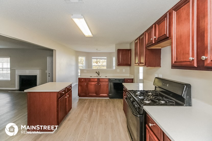 a kitchen with wood flooring and white counter tops and black appliances
