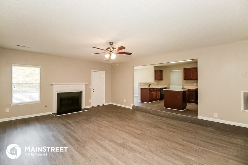 an empty living room with a fireplace and a ceiling fan