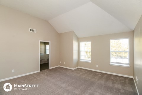 the spacious living room with carpet and two windows