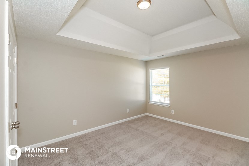 the spacious living room has a vaulted ceiling and a window