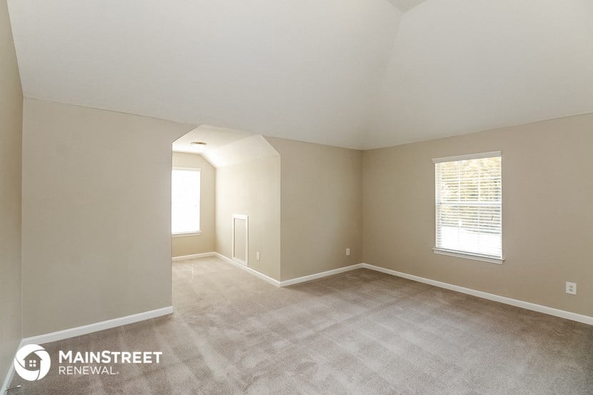 the spacious living room with carpeting and a window
