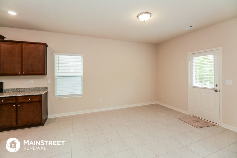 an empty kitchen with a white tile floor and a white door