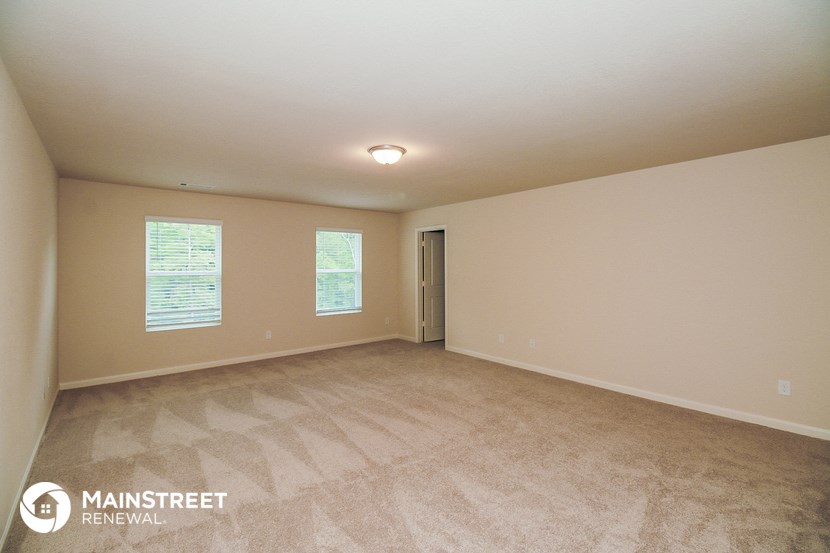 the spacious living room with carpeting and a door to the bathroom