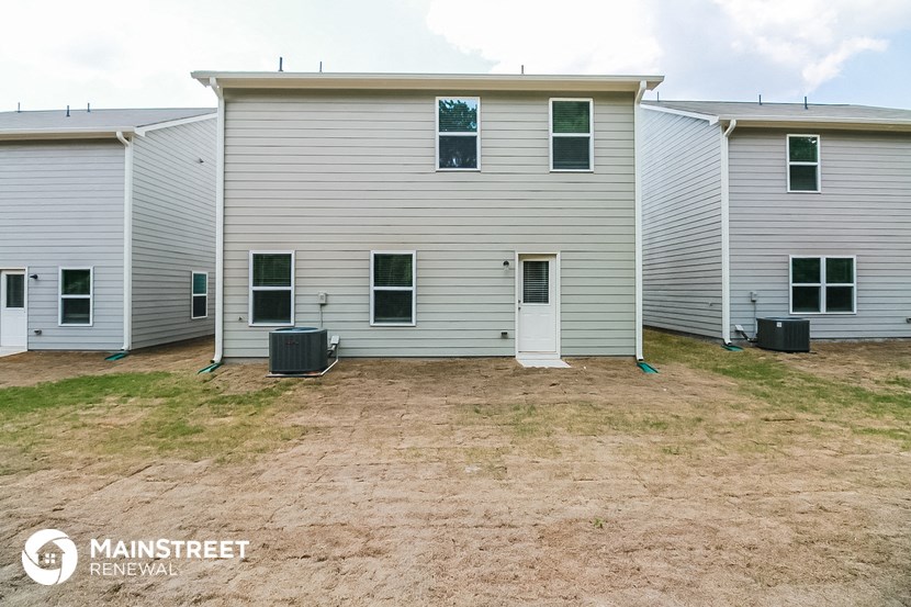 the exterior of a home with a dirt yard and three white houses