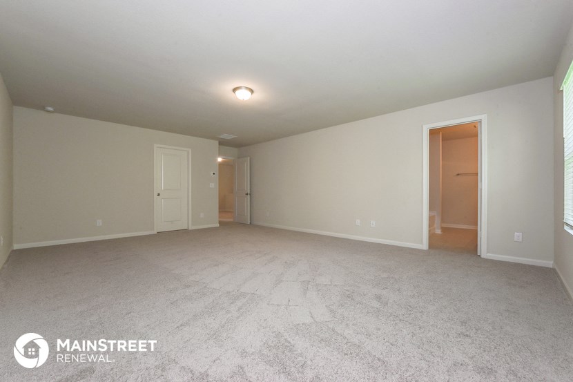 the spacious living room with white carpet and white walls