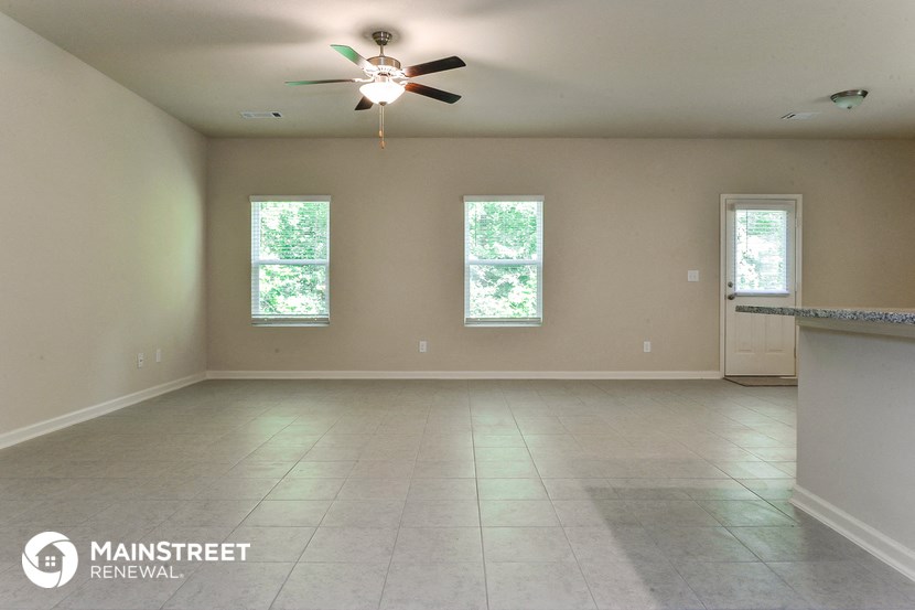 an empty living room with a ceiling fan