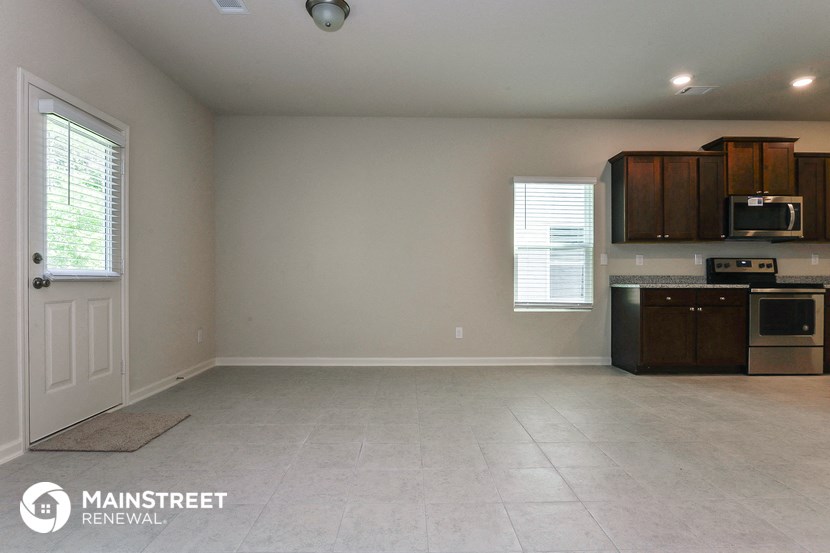 an empty kitchen with a white tile floor and wooden cabinets