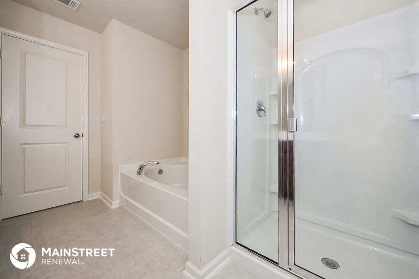 a bathroom with a shower and a tub and a white door