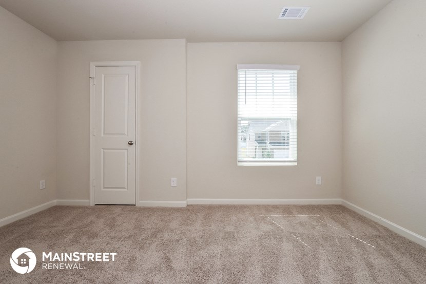 a room with carpet and a white door and a window